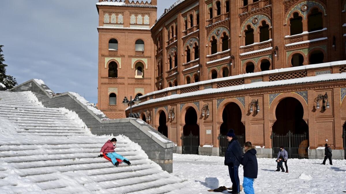 A woman slides down steps outside the Las Ventas bullring in Madrid on January 10, 2021. Snowstorms in Spain left three people dead and caused chaos across much of the country, trapping motorists and shutting down the capital's air and rail links. Gabriel BOUYS / AFP