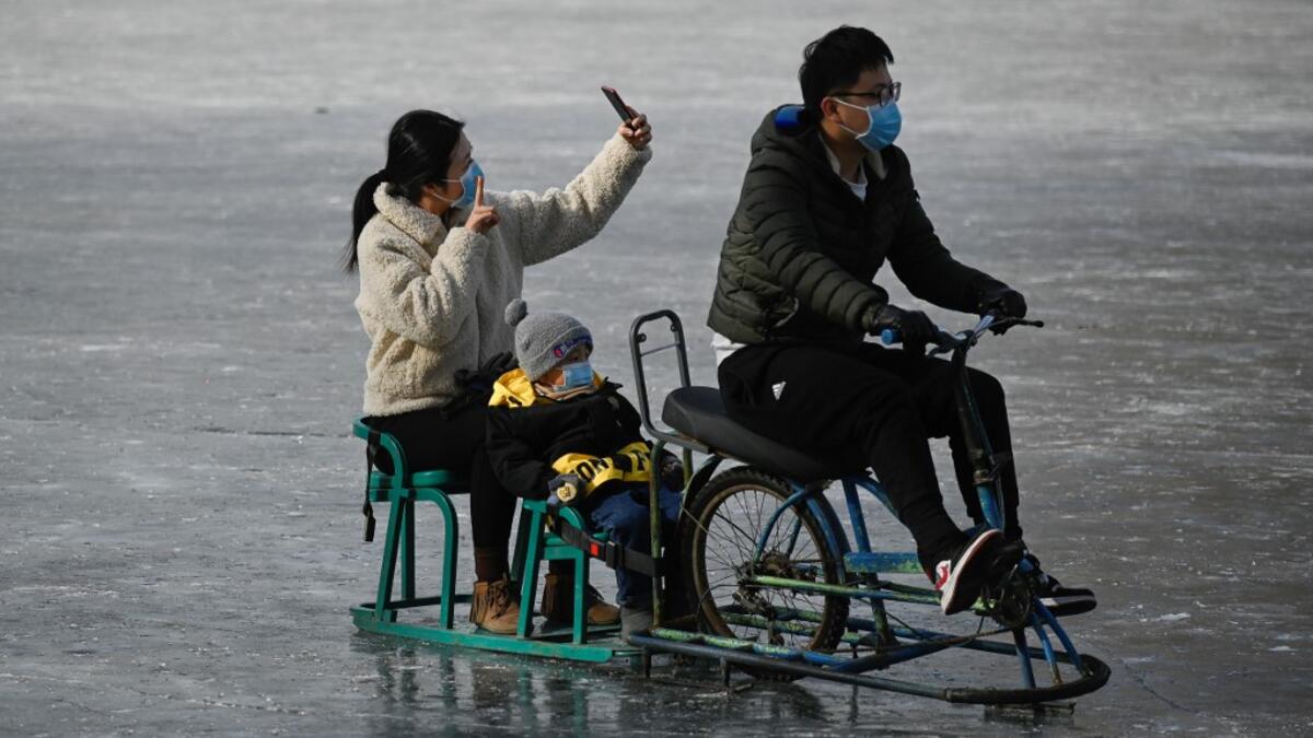 A family use mobile phone to take a selfie as they ride sled on a frozen lake in Beijing on January 12, 2021. WANG Zhao / AFP