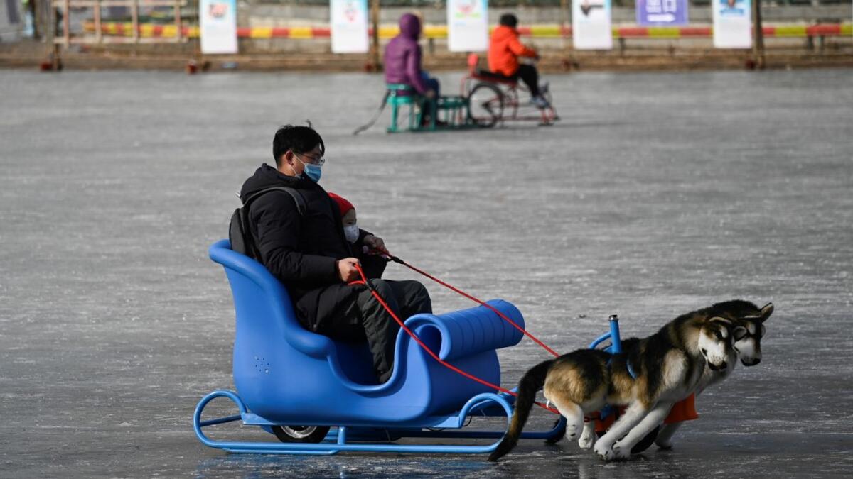 A man and a child use a sled on a frozen lake in Beijing on January 12, 2021. WANG Zhao / AFP