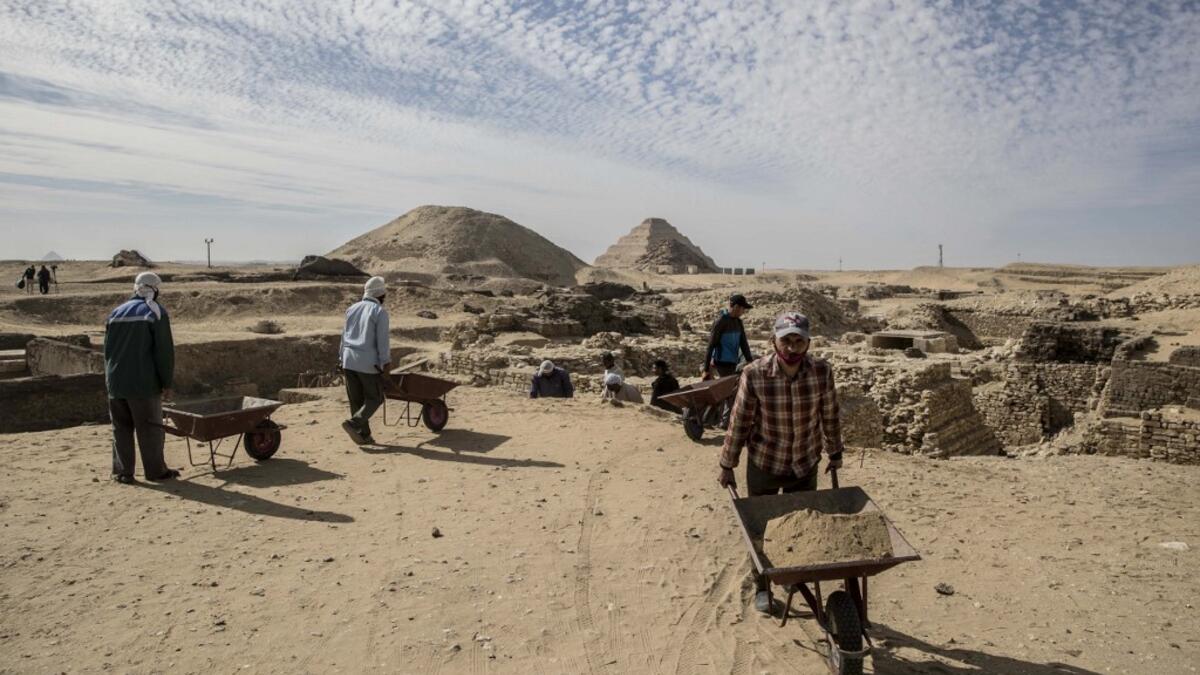 Workers excavate a site during the official announcement of the discovery by an Egyptian archaeological mission of a new trove of treasures at Egypt's Saqqara necropolis south of Cairo, on January 17, 2021. The discovery at the necropolis which lies 30kms south of the Egyptian capital, includes the funerary temple of Queen Naert, wife of King Teti, as well as burial shafts, coffins, and mummies dating back to nearly 3000 years ago during the New Kingdom. Khaled DESOUKI / AFP