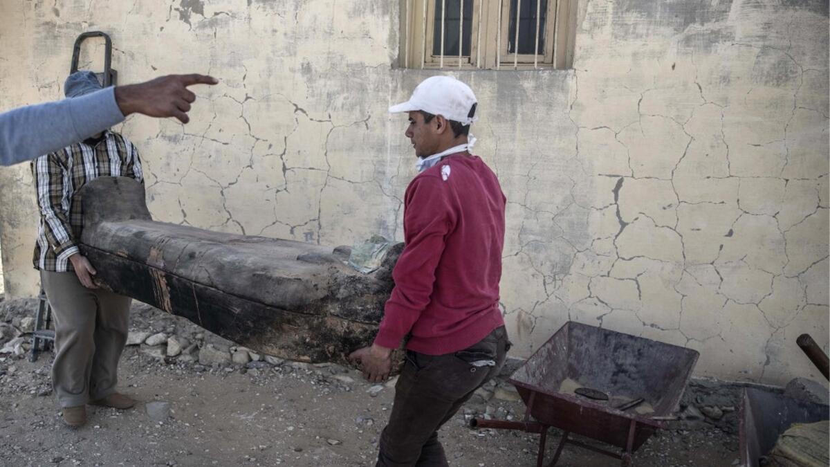 Workers transport a wooden sarcophagus for display ahead of the official announcement of the discovery by an Egyptian archaeological mission of a new trove of treasures at Egypt's Saqqara necropolis south of Cairo, on January 17, 2021. The discovery at the necropolis which lies 30kms south of the Egyptian capital, includes the funerary temple of Queen Naert, wife of King Teti, as well as burial shafts, coffins, and mummies dating back to nearly 3000 years ago during the New Kingdom. Khaled DESOUKI / AFP