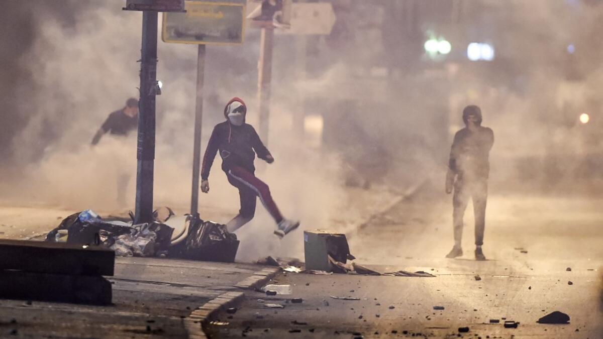 Protesters stand amidst fumes as they block a street during clashes with security forces in the Ettadhamen city suburb on the northwestwern outskirts of Tunisia's capital Tunis on January 17, 2021, amidst a wave of nightly protests in the North African country. FETHI BELAID / AFP