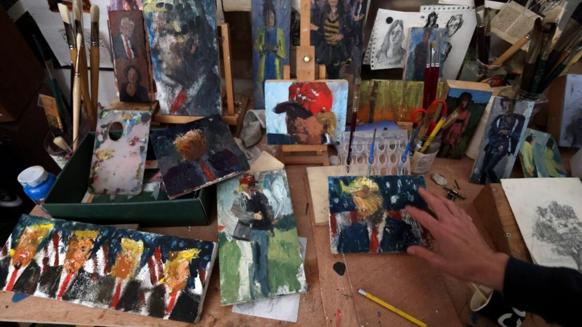 Israeli painter Iddo Markus arranges his paintings of former US president Donald Trump, at his studio in the northern port city of Haifa, on January 22, 2021. Markus became fascinated by the "tragic figure" of Donald Trump, and the walls and floor of his studio are packed with some 120 portraits of the former US presidents. Emmanuel DUNAND / AFP