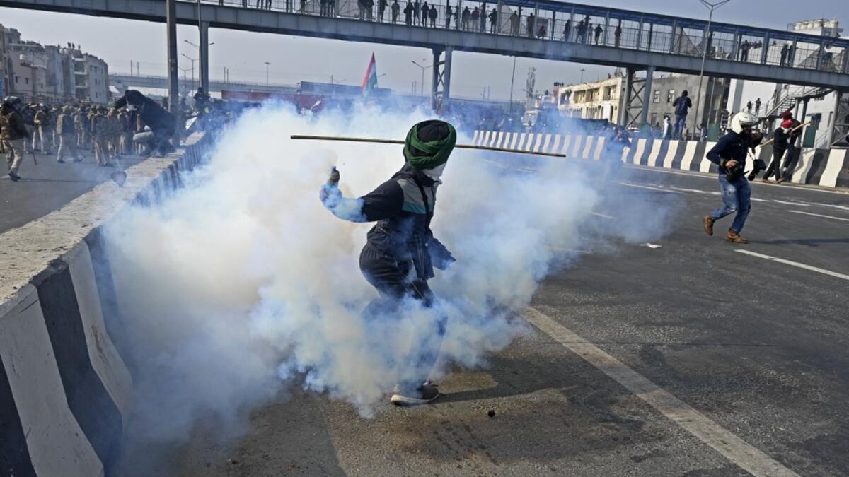 A farmer throws back a tear gas shell towards police during a tractor rally as farmers continue to protest against the central government's recent agricultural reforms in New Delhi on January 26, 2021. Sajjad HUSSAIN / AFP