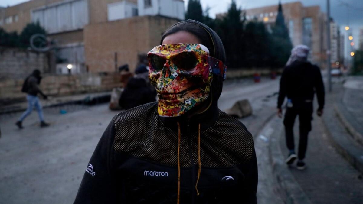 A Lebanese anti-government protester wears a mask during clashes with security forces in front of the Serail (headquarters of the Governorate), in the northern port city of Tripoli, following a demonstration to protest against the economic situation, on January 28, 2021. Tripoli was already one of Lebanon's poorest areas before the coronavirus pandemic piled new misery onto a chronic economic crisis. Many of its residents have been left without an income since Lebanon imposed a full lockdown earlier this mo