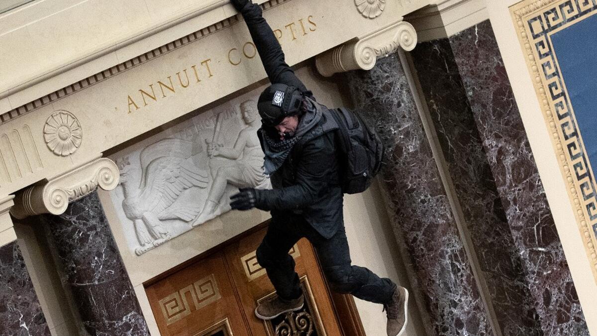 A protester supporting U.S. President Donald Trump jumps from the public gallery to the floor of the Senate chamber at the U.S. Capitol Building on January 06, 2021 in Washington, DC. Congress held a joint session today to ratify President-elect Joe Biden's 306-232 Electoral College win over President Donald Trump. A group of Republican senators said they would reject the Electoral College votes of several states unless Congress appointed a commission to audit the election results Win McNamee/Getty Images/A