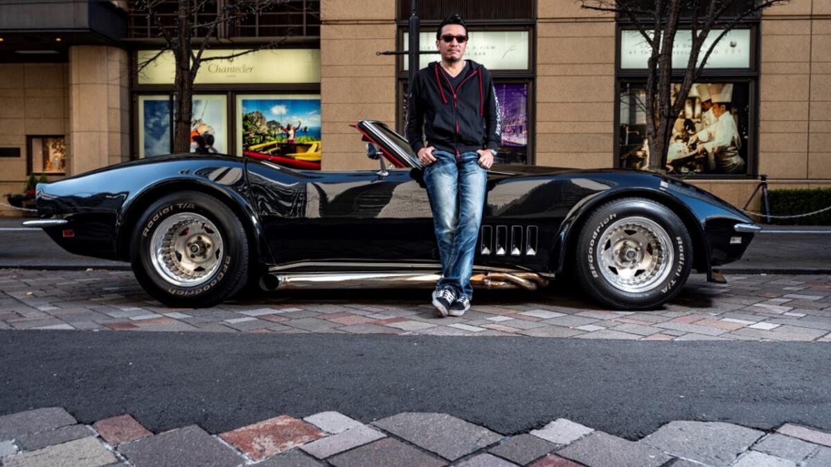This picture taken on January 16, 2021 shows real estate and construction business owner Atsushi Hasegawa posing for a photo with a 1969 Chevrolet Corvette during a gathering of auto enthusiasts in Tokyo. A loose club of fans rolls up most weekends in central Tokyo to show off their Cadillacs, Chevrolets and other modern classic vehicles from the mid to late 20th century. Philip FONG / AFP