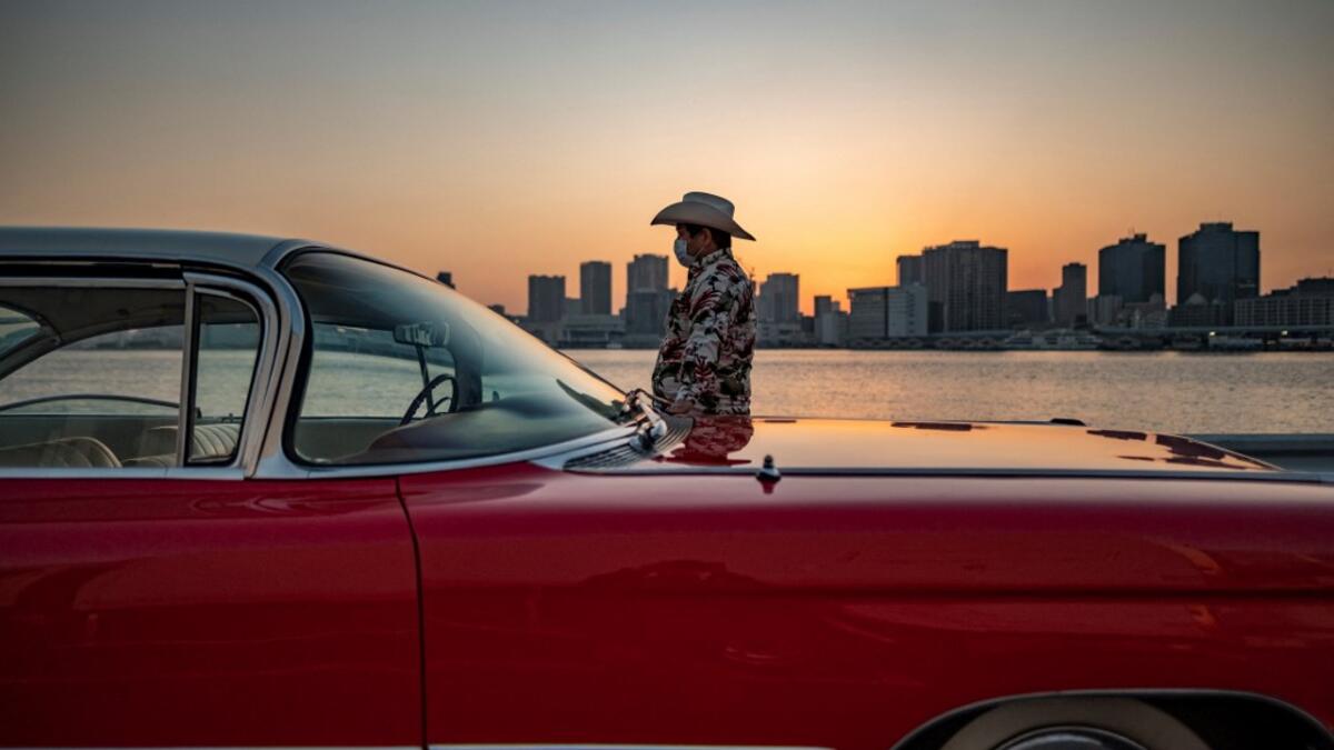 This picture taken on January 16, 2021 shows Hiroyuki Wada, who runs a vintage car service company, standing next to a 1959 Cadillac Coupe DeVille after a gathering of auto enthusiasts in Tokyo. A loose club of fans rolls up most weekends in central Tokyo to show off their Cadillacs, Chevrolets and other modern classic vehicles from the mid to late 20th century. Philip FONG / AFP