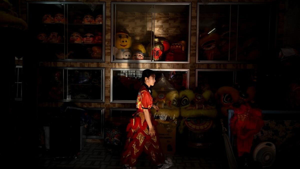 This photograph taken on January 20, 2021 shows Huynh Thi Kim Dieu walking past a room full of costumes before practice at the Tu Anh Duong lion and dragon dance school in Can Tho city in southern Vietnam's Mekong Delta. Manan VATSYAYANA / AFP