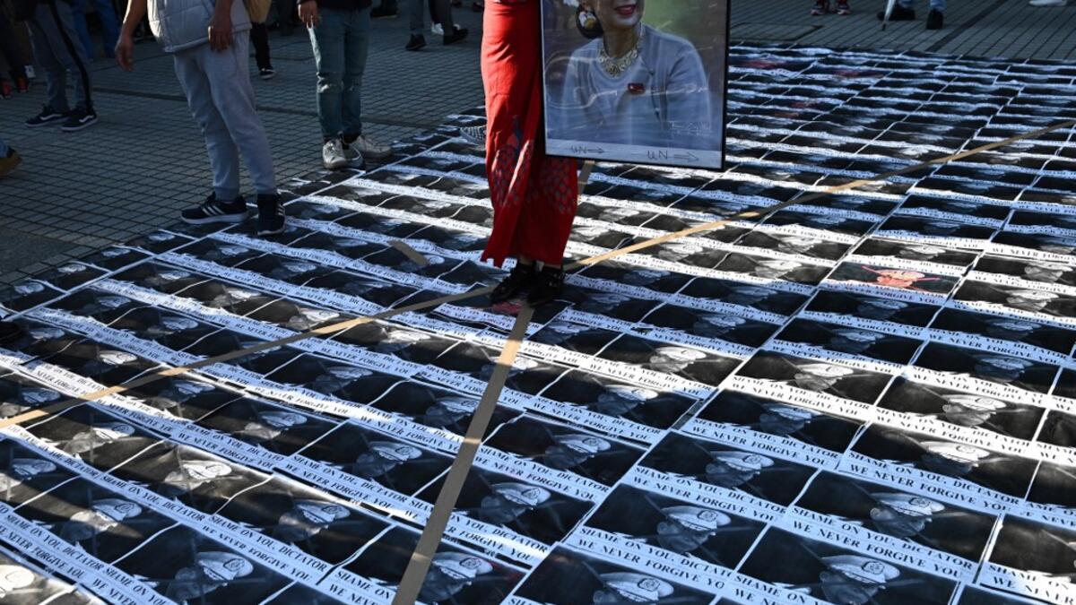 A Myanmar activist holds a portrait of Myanmar's de facto leader Aung San Suu Kyi as portraits of the country's military general Min Aung Hlaing are seen on the floor during a a protest outside the United Nations University building in Tokyo on February 1, 2021 following a military coup in the country by a general after arresting civilian leader Aung San Suu Kyi and other senior officials. Philip FONG / AFP