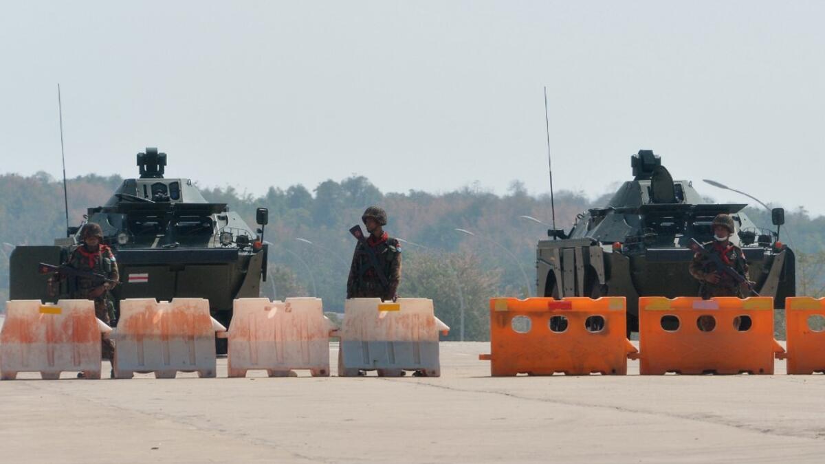 Soldiers stand guard on a blockaded road to Myanmar's parliament in Naypyidaw on February 1, 2021, after the military detained the country's de facto leader Aung San Suu Kyi and the country's president in a coup. STR / AFP