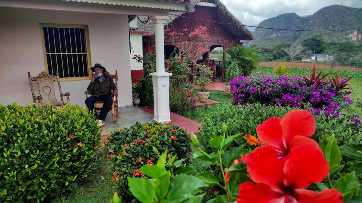 Eduardo Hernandez, owner of a private restaurant and a tobacco cultivator, smokes a cigar in his house in Vinales, Cuba, on January 28, 2021. At the foot of the majestic rock formations of Vinales, the terraces of the restaurants look empty and the lodgings have closed. With the arrival of COVID-19, the incipient prosperity of this Cuban town came to a halt and people abandoned tourism jobs to return to work the land. YAMIL LAGE / AFP