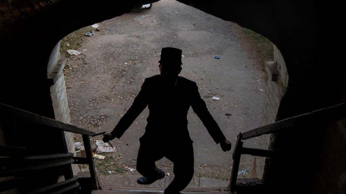 In this picture taken on February 9, 2021, street actor Usman Khan, dressed up as silent film star Charlie Chaplin, performs in the Pakistan's northwestern city of Peshawar. Wearing a bowler hat and familiar toothbrush moustache, Pakistan's Usman Khan darts through traffic swinging a cane, teasing motorists and shopkeepers for laughs and a few rupees with a Charlie Chaplin impersonation that has become a viral sensation.  Abdul MAJEED / AFP