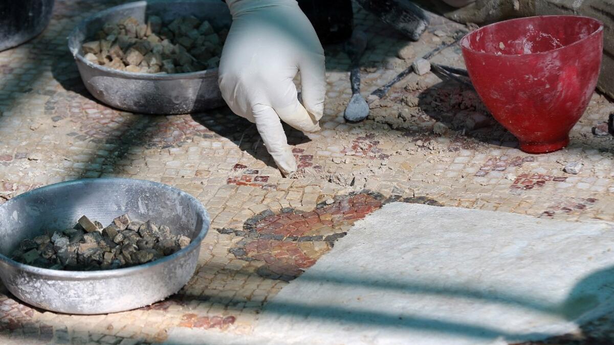 A worker employed by a pilot project run by the UN cultural agency UNESCO, restores a mosaic floor at an ancient church complex, in the small town of Rihab, some 70 kilometres north of the Jordanian capital Amman, on February 9, 2021. In the ruins of the ancient Byzantine church in Jordan, local townspeople and Syrian refugees work side by side on a project that unites preserving cultural heritage and fighting poverty.  Khalil MAZRAAWI / afp