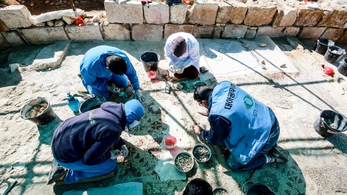 Workers employed by a pilot project run by the UN cultural agency UNESCO, restore a mosaic floor at an ancient church complex, in the small town of Rihab, some 70 kilometres north of the Jordanian capital Amman, on February 9, 2021. In the ruins of the ancient Byzantine church in Jordan, local townspeople and Syrian refugees work side by side on a project that unites preserving cultural heritage and fighting poverty.  Khalil MAZRAAWI / afp