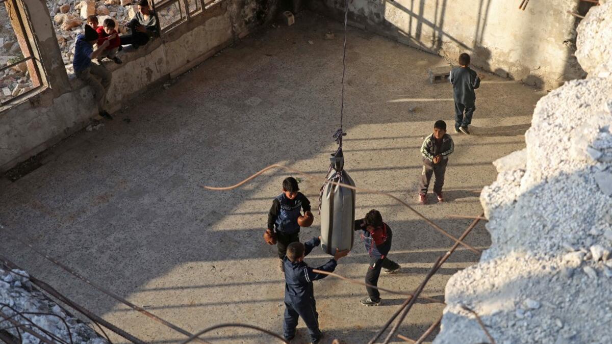 Syrian youths take part in a boxing workout held by local boxer Ahmad Dwara (unseen) inside a damaged building in the town of Atareb in the rebel-held western countryside of Syria's Aleppo province, on February 11, 2021. AAREF WATAD / AFP