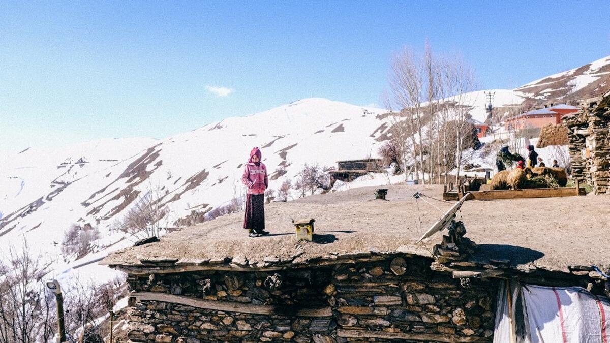 In this photograph taken on February 15, 2021, Kurdish girl looks at members of the Bahcesaray public hospital vaccination team as they arrive at the village of Guneyyamac in eastern Turkey, as part of an expedition to vaccinate residents of 65 years old or above with Sinovac's CoronaVac Covid-19 vaccine. Turkey's population of more than 83 million is spread out across Europe and Asia and covers some seemingly impregnable terrain. The vaccination effort with China's CoronaVac jab kicked off with a bang in m