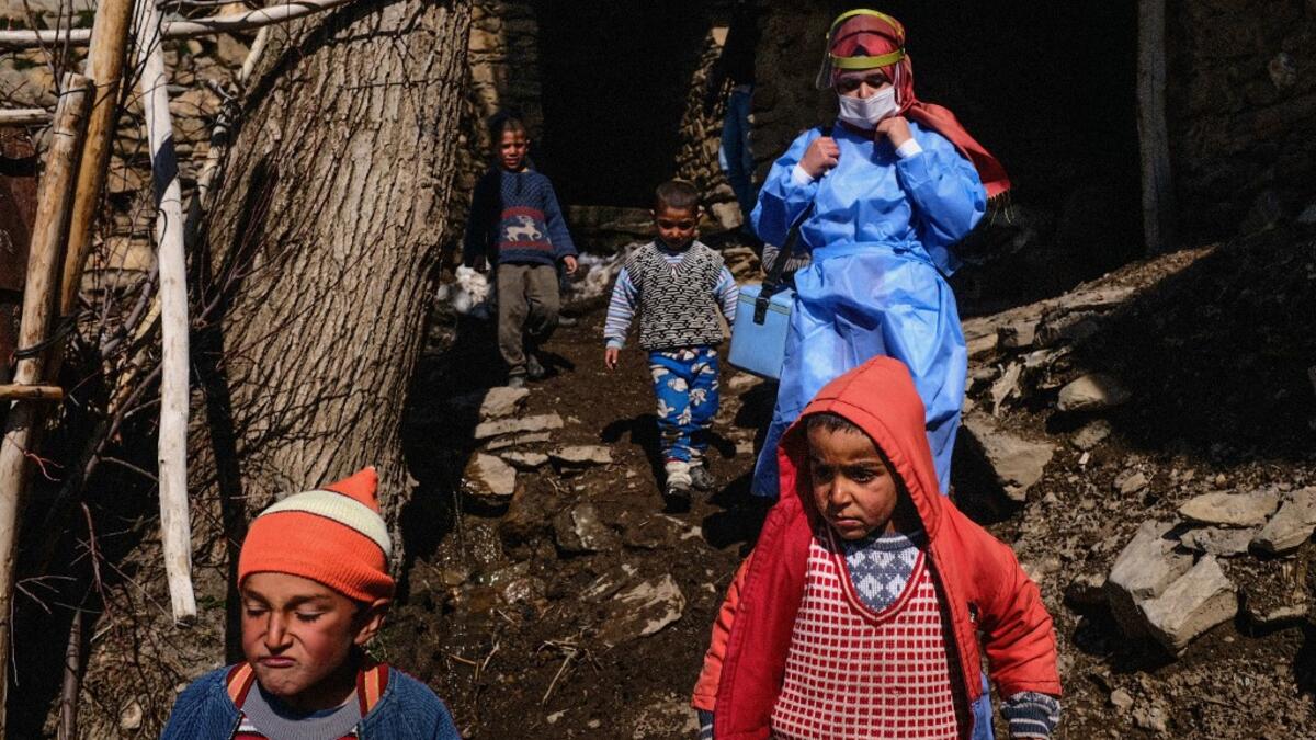 In this photograph taken on February 15, 2021, nurse Yildiz Ayten (rear R) from Bahcesaray public hospital vaccination team is escorted by Kurdish children as she searches for old people at the village of Guneyyamac in eastern Turkey, as part of an expedition to vaccinate residents of 65 years old or above with Sinovac's CoronaVac Covid-19 vaccine. Turkey's population of more than 83 million is spread out across Europe and Asia and covers some seemingly impregnable terrain. The vaccination effort with China