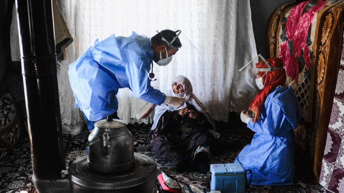 In this photograph taken on February 15, 2021, Berfo Arsakay (C), 101 years old, prepares to receive a vaccine from doctor Akay Kaya (L) and nurse Yildiz Ayten (R) from the Bahcesaray public hospital vaccination team, at the village of Guneyyamac in eastern Turkey, as part of an expedition to vaccinate residents of 65 years old or above with Sinovac's CoronaVac Covid-19 vaccine. Turkey's population of more than 83 million is spread out across Europe and Asia and covers some seemingly impregnable terrain. Th