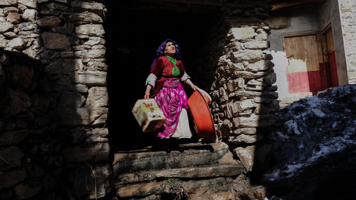 In this photograph taken on February 15, 2021, a Kurdish woman carries plastic boxes in the streets of the village of Guneyyamac in eastern Turkey, as part of an expedition organised by the Bahcesaray public hospital vaccination team, to vaccinate residents of 65 years old or above with Sinovac's CoronaVac Covid-19 vaccine. Turkey's population of more than 83 million is spread out across Europe and Asia and covers some seemingly impregnable terrain. The vaccination effort with China's CoronaVac jab kicked o