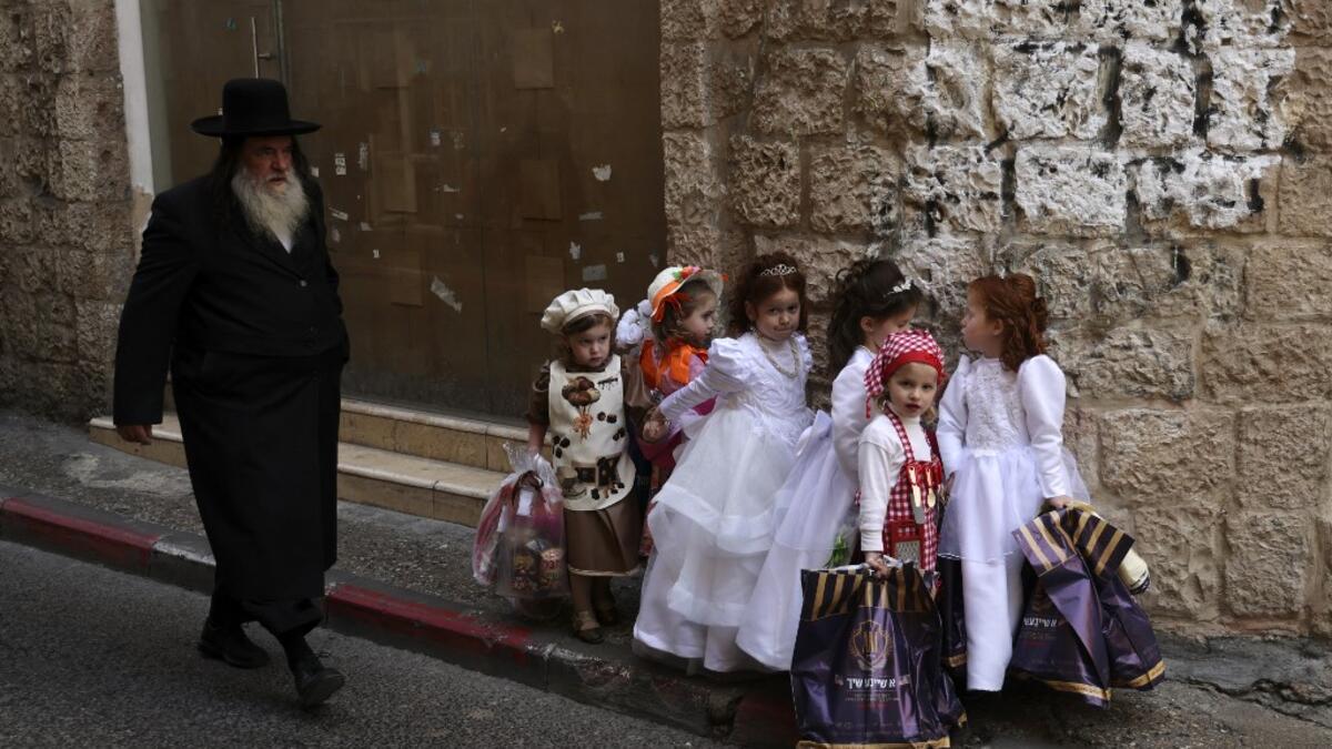 Ultra-Orthodox Jewish children dressed in costumes to celebrate Purim, walk in the street a day ahead of the official holiday, in the Mea Shearim neighbourhood in Jerusalem, on February 24, 2021. The carnival-like Purim holiday is celebrated with parades and costume parties to commemorate biblical story of the deliverance of the Jewish people from a plot to exterminate them in the ancient Persian empire , as recorded in the Book of Esther. MENAHEM KAHANA / AFP