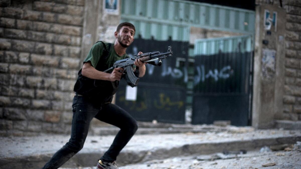 Syrian rebel aims his weapon during clashes with government forces