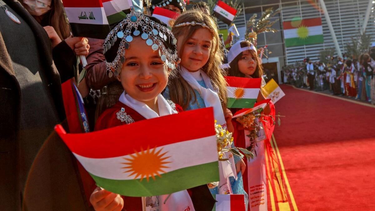 Irqi children wave Kurdish flags as they welcome Pope Francis