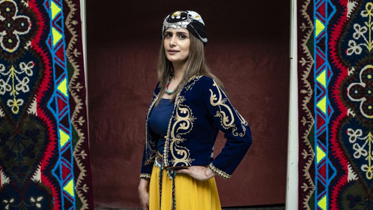 A Syrian Kurdish woman in traditional attire poses for a picture