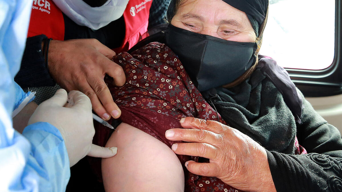 حافلات في الأردن: يصل اللاجئون السوريون في باص الى مركز طبي لتلقي في محافظة المفرق قرب الحدود السورية، ولا يتردد الفريق في تلقيح فاطمة علي التي تعاني من آلام في المفاصل، داخل الحافلة.