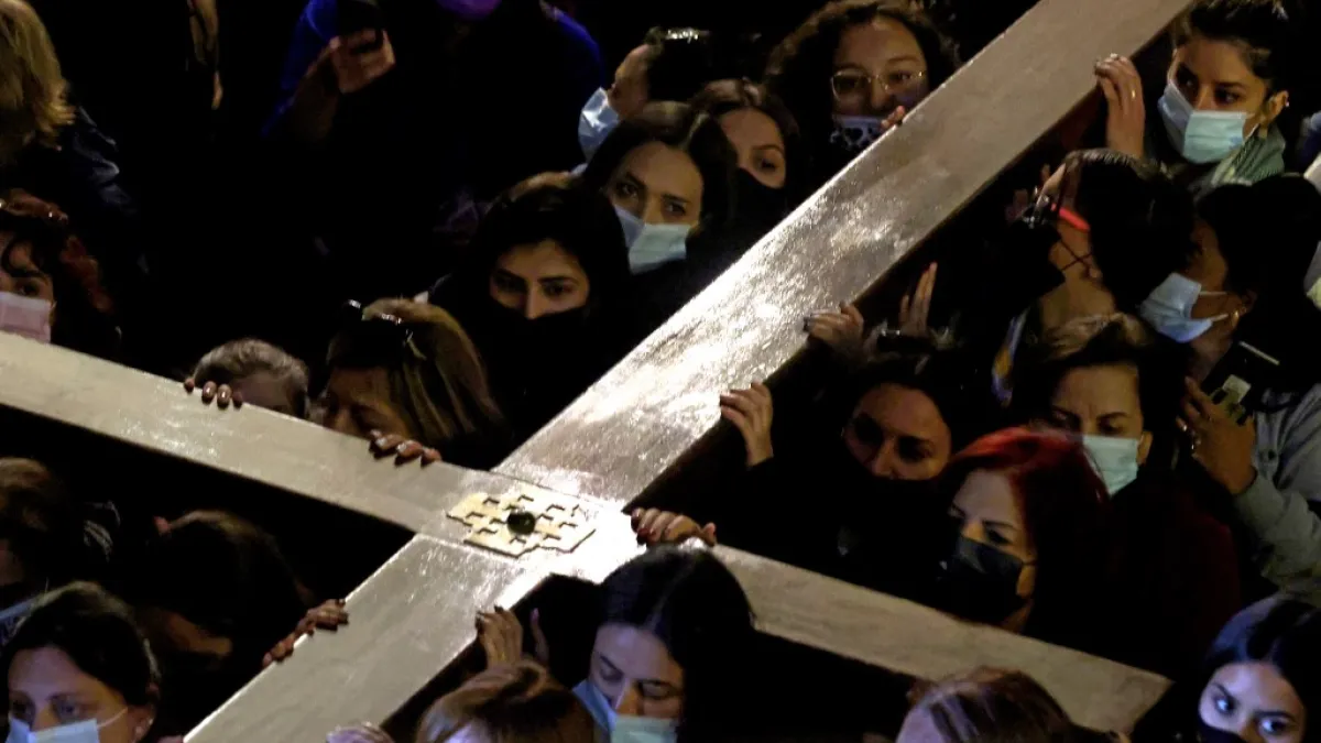 Christian worshippers carrying a wooden cross walk inside the Church of the Holy Sepulchre,