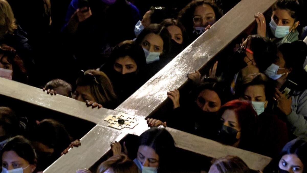 Christian worshippers carrying a wooden cross walk inside the Church of the Holy Sepulchre,