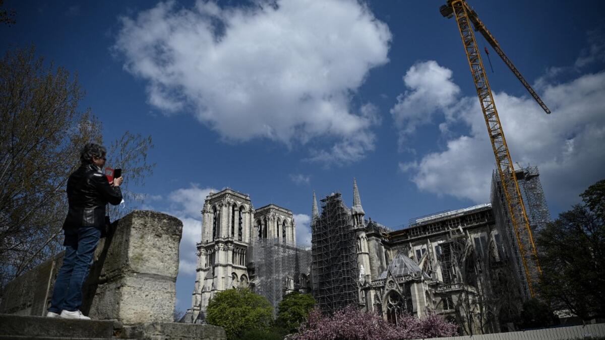 A woman takes pictures of Notre-Dame de Paris cathedral