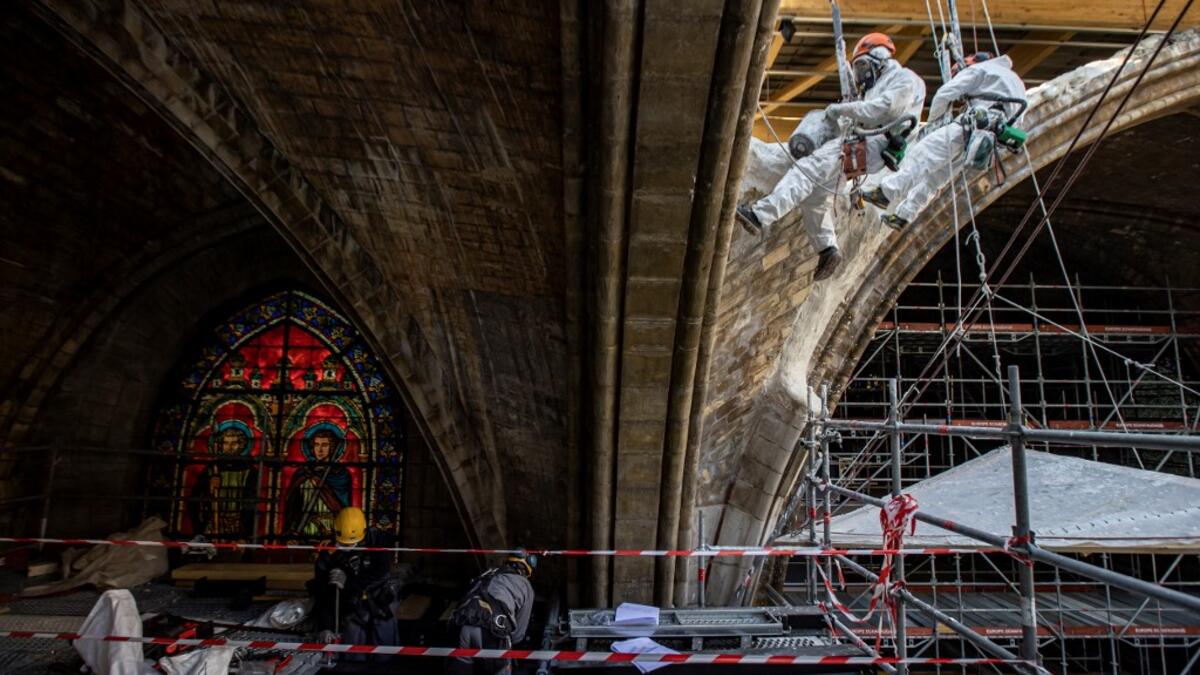 Rope access technicians plaster stonework on a damaged vault of the Notre-Dame de Paris Cathedral