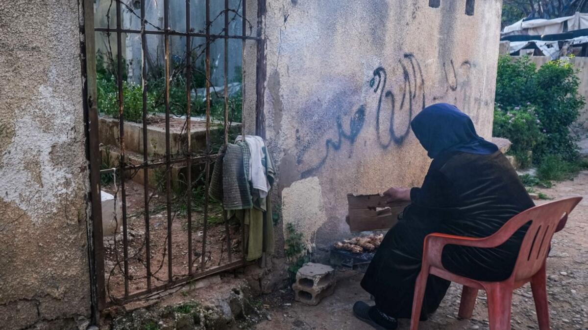 A woman grills chicken near a grave, as she prepares the fast-breaking "Iftar" meal