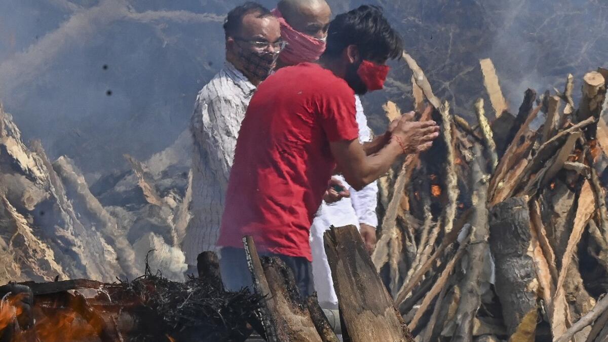 A man reacts as he performs the last rites of his relative amid the funeral pyres of victims who died of the Covid-19 coronavirus during mass cremation held at a crematorium in New Delhi