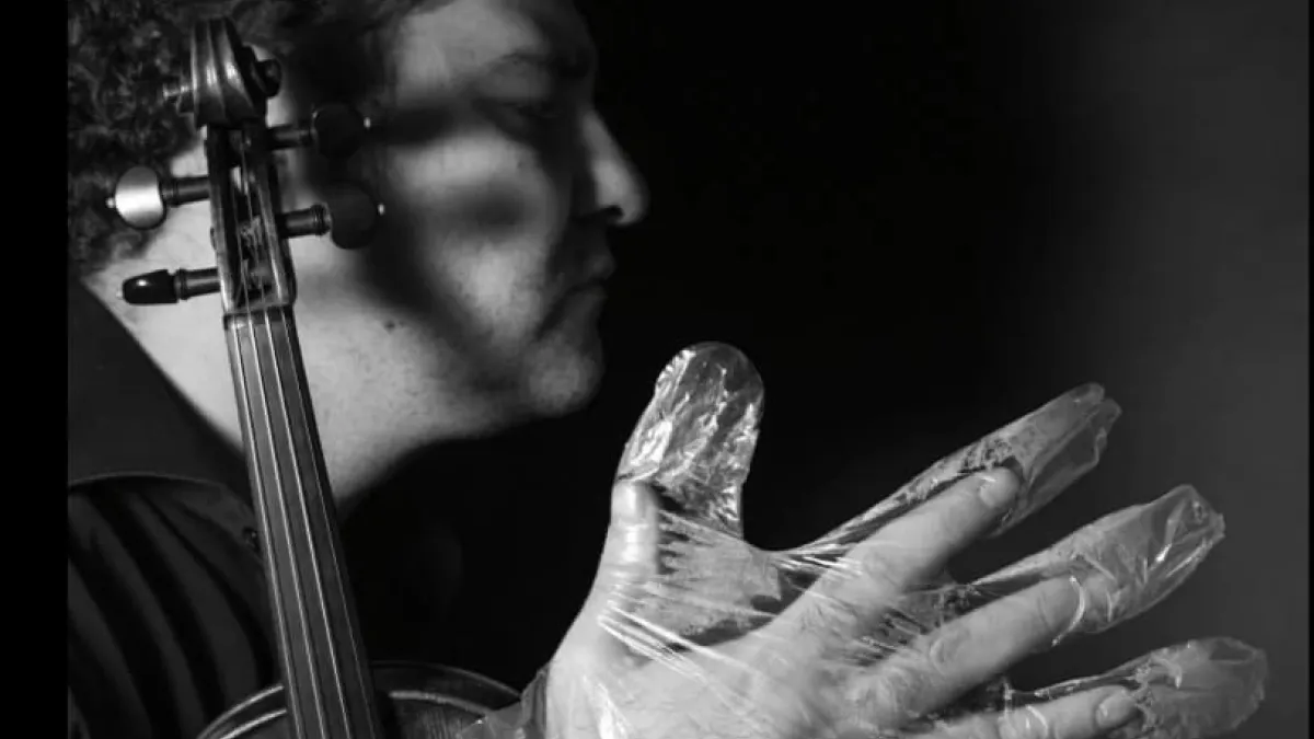 A musician in foil gloves is playing an instrument