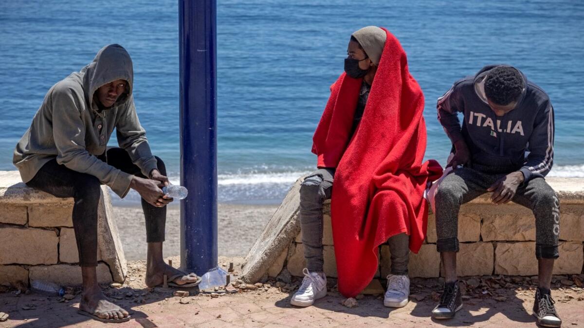 Subsaharian migants sit on a sea wall in the northern town of Fnideq as they attempt to cross the border from Morocco to Spain's North African enclave of Ceuta on May 19, 2021. Spain stepped up diplomatic pressure on Rabat as its prime minister flew into Ceuta, vowing to "restore order" in the North African enclave after a record 8,000 migrants reached its beaches from Morocco