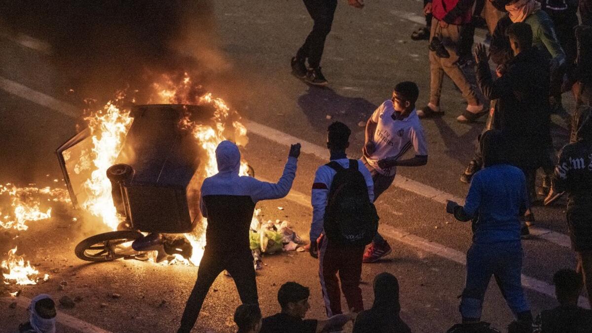 Migrants burn a skip during clashes with Moroccan riot police in the northern town of Fnideq, close to the border between Morocco and Spain's North African enclave of Ceuta on May 19, 2021. Migrants were still trying to cross from Morocco into the Spanish enclave of Ceuta on May 19, 2021, after a record 8,000 people poured over the border this week, escalating tensions between Rabat and Madrid. Some 5,600 migrants had already been sent back, Madrid said