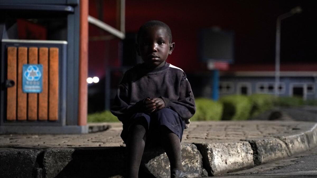 A lost child sits on a curb as Congolese people flee from Goma, Democratic Republic of Congo (DRC), after the Nyiragongo volcano erupted, at the border point known as "Petite Barriere" in Gisenyi, Rwanda, on May 23, 2021. The government of the Democratic Republic of Congo has ordered the evacuation of the eastern city of Goma after the eruption of Mount Nyiragongo overlooking the border city. The lava reached the city's airport early Sunday, with an official from Virunga National Park