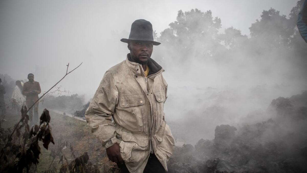 Men cross the front of the still smoking lava rocks from an eruption of the Mount Nyiragongo on May 23, 2021 in Goma in the East of the Democratic Republic of Congo. A river of boiling lava came to a halt on the outskirts of Goma Sunday, sparing the city in eastern DR Congo