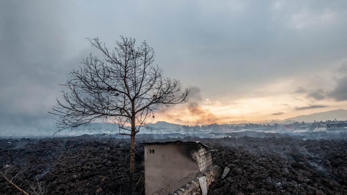 This general view shows a structure still standing, surrounded by the lava who flew during yesterday's eruption on May 23, 2021. A river of boiling lava came to a halt on the outskirts of Goma Sunday, sparing the city in eastern DR Congo from disaster after the nighttime eruption of Mount Nyiragongo sent thousands of terrified residents fleeing in panic. Fire and strong fumes emanated from the blackish molten rock as it swallowed up houses, heading towards Goma airport on the shores of Lake Kivu