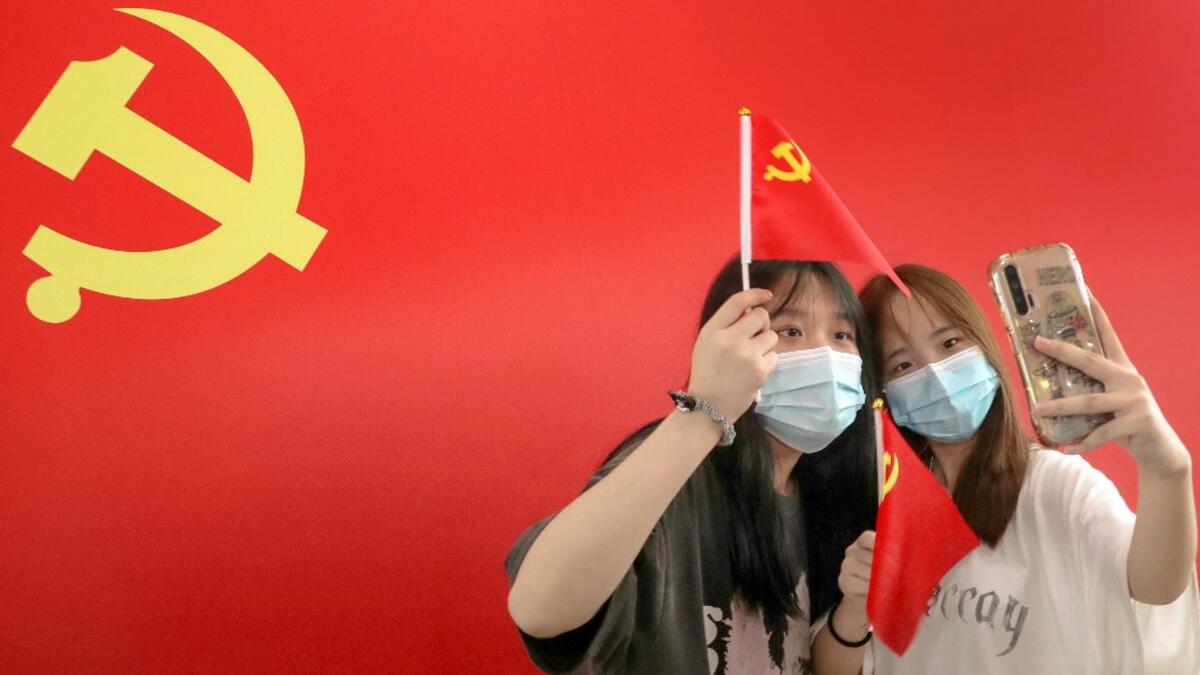 Passengers take photos with a flag of the Communist Party of China at the Nantong Railway Station in China's eastern Jiangsu province on July 1, 2021, during celebrations to mark the 100th anniversary of the founding of the Communist Party of China