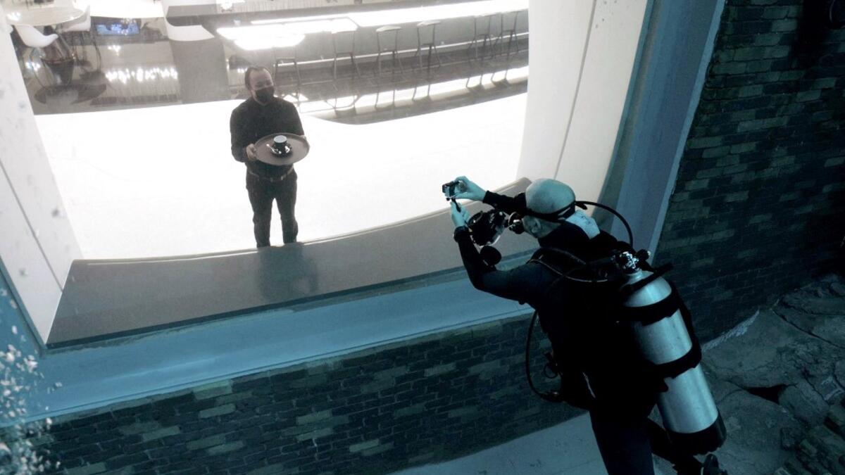 A diver experiencing Deep Dive Dubai, the deepest swimming pool in the world reaching 60m, photographs a waiter through a viewing glass, on July 10, 2021. The city of superlatives, with the world's tallest tower among its many records, Dubai now has the deepest swimming pool on the planet complete with a "sunken city" for divers to explore. GIUSEPPE CACACE / AFP