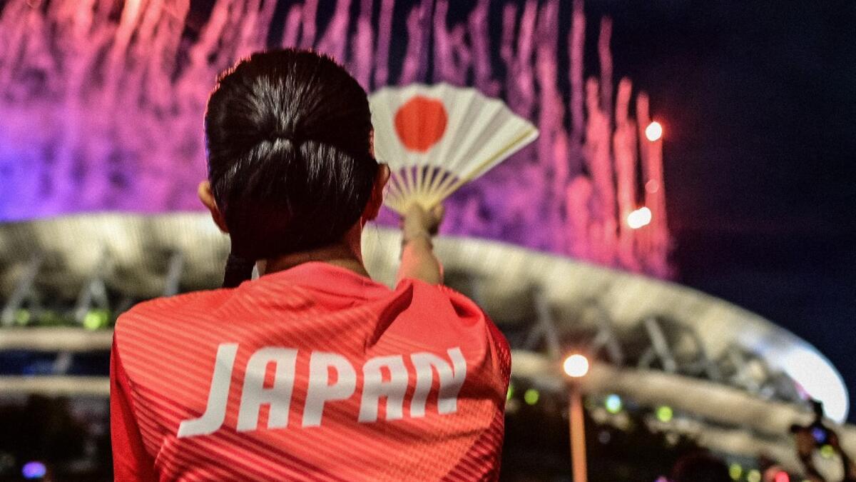 A Japanese supporter looks on as fireworks light up the sky over the Olympic Stadium during the opening ceremony of the Tokyo 2020 Olympic Games,