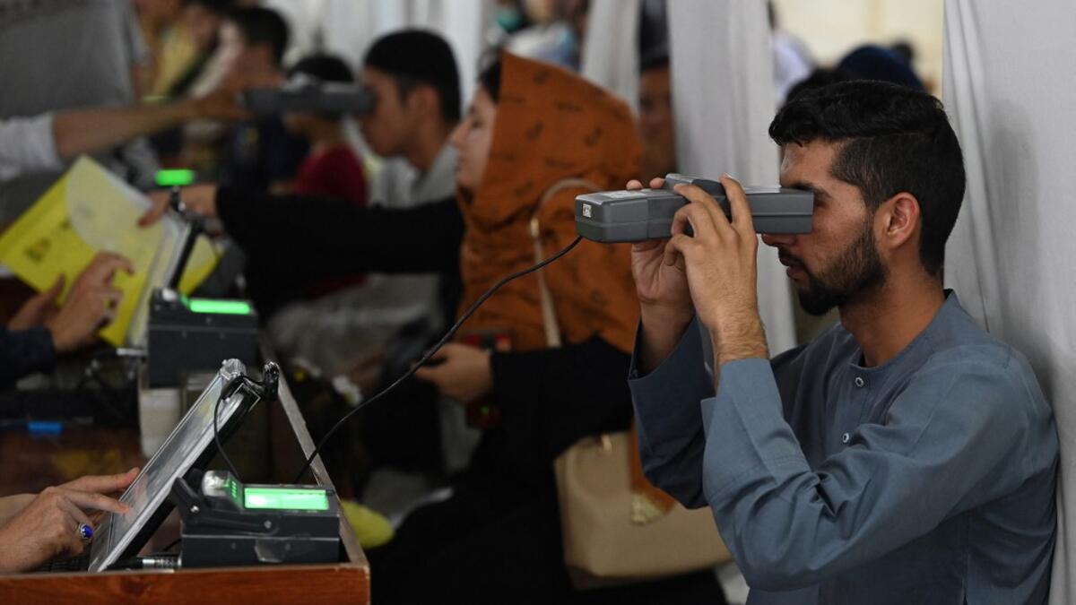 A man looks through an optical biometric reader to submit his passport application at an office in Kabul on July 25, 2021. Dozens begin lining up at the passport office in Kabul before dawn most days, and by eight in the morning the queue already stretches for a good hundred metres.