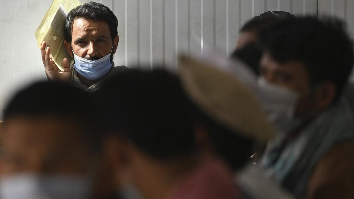 People wait to process a biometric registration to submit their passport applications at an office in Kabul on July 25, 2021. Dozens begin lining up at the passport office in Kabul before dawn most days, and by eight in the morning the queue already stretches for a good hundred metres.