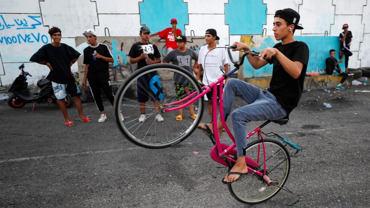 An Iraqi youth performs stunts on a bicycle in the Jadriya district of Baghdad on August 6, 2021. All dressed up and nowhere to go: many young Iraqis in Baghdad make an effort to be hip, even as they admit their country may have no future.