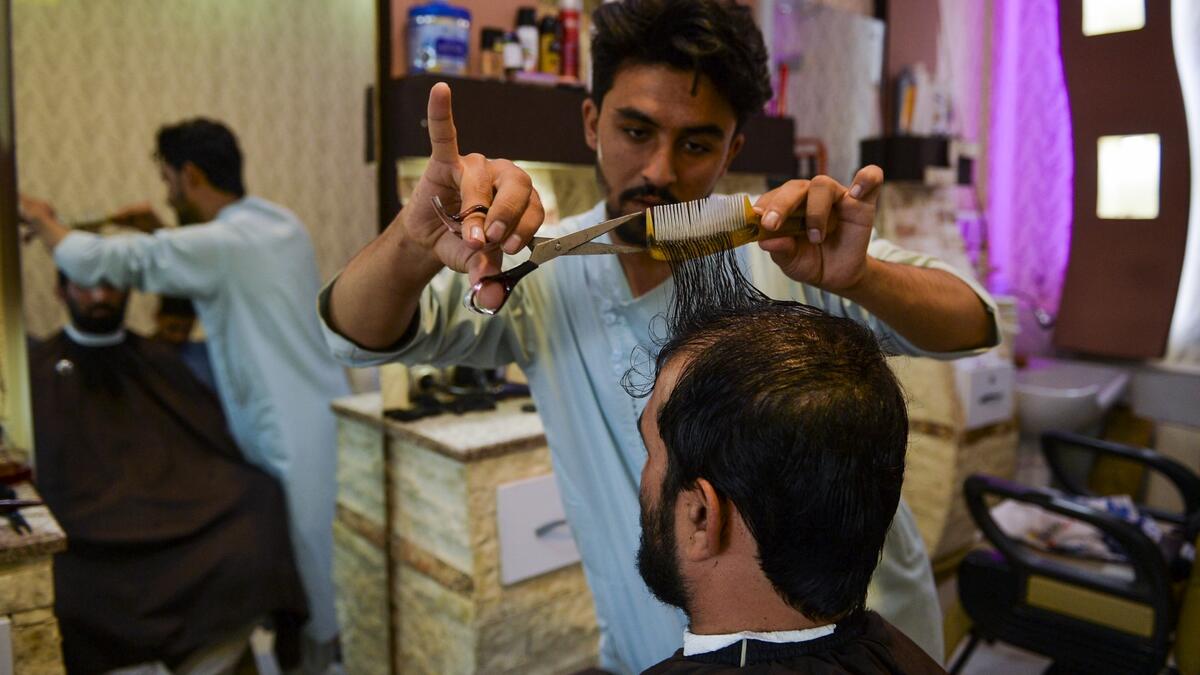 In this picture taken on September 19, 2021, a barber attends a customer at his shop in Herat.
