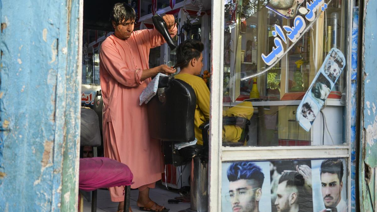 In this picture taken on September 19, 2021, 24-year old Nader Shah attends a customer at his barbershop in Herat.