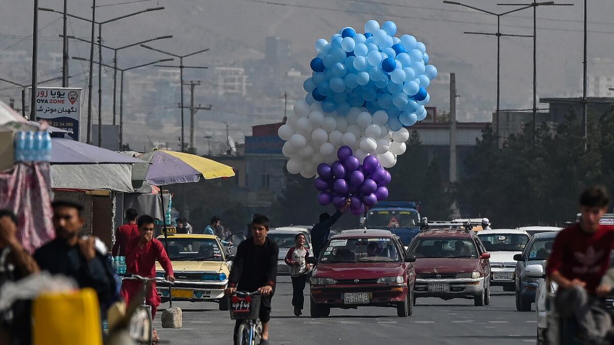 An Afghan man selling balloons rides in a car in Kabul on September 21, 2021.